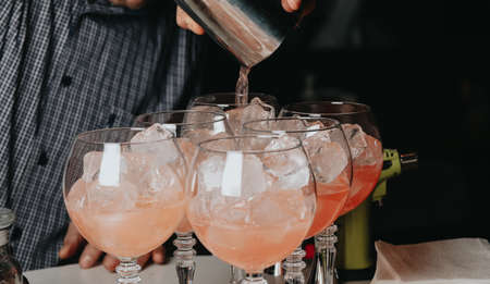 Cocktails with champagne in wine glasses on the bar table in the pub or restaurant with the bartender.の写真素材