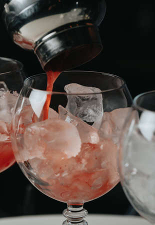 Cocktails with champagne in wine glasses on the bar table in the pub or restaurant with the bartender.の写真素材