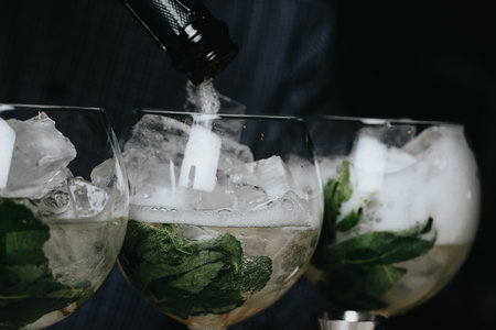 Cocktails with champagne in wine glasses on the bar table in the pub or restaurant with the bartender.の写真素材
