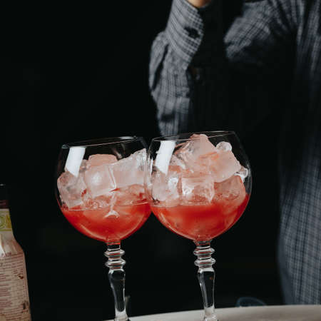 Cocktails with champagne in wine glasses on the bar table in the pub or restaurant with the bartender.の写真素材