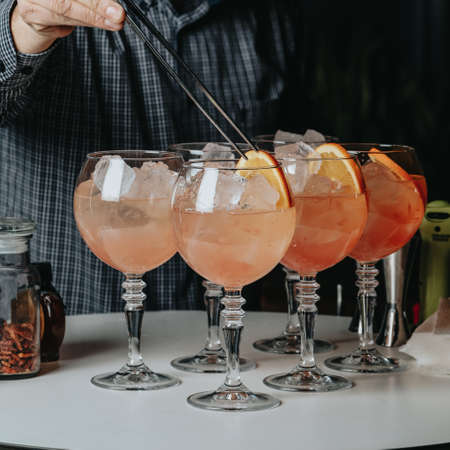 Cocktails with champagne in wine glasses on the bar table in the pub or restaurant with the bartender.の写真素材