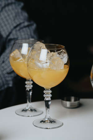 Cocktails with champagne in wine glasses on the bar table in the pub or restaurant with the bartender.の写真素材