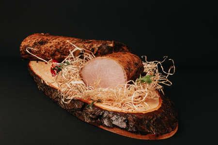 Smoked pork muscles sausage and bacon on a wooden board with the addition of fresh aromatic herbs, garlic, sea salt and pepper.の写真素材