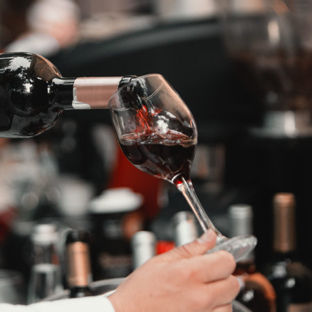 The waiter serves rose, red and white wine from the wine bottle in the wine glass at an event.