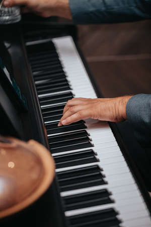 The hands of a musician playing the piano closeup in dark tones. Good for posters or media posts.の写真素材
