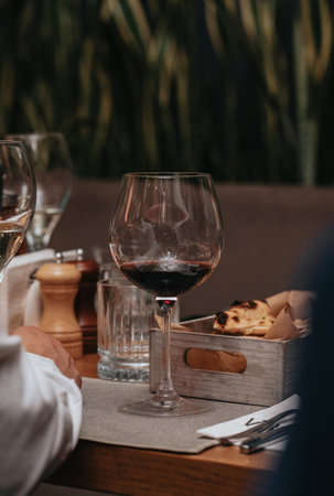 Elegant waiter pours red wine from bottle into glass at restaurant. Sommelier tasting wine in restaurant. Copy space for text menu elegant or recipe on dark background.の写真素材