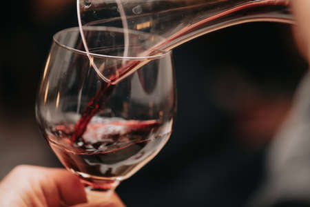 Glass of red wine in hand at a special event, a specific tasting of alcoholic beverages.の写真素材