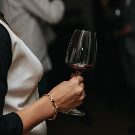 Glass of red wine seen close up in the hand at a wine tasting with friendsの写真素材