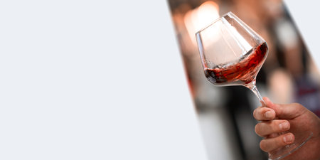 Glass of red wine in hand on tasting of alcoholic beverages image for banners, poster, magazine, flayer, mockup.の写真素材