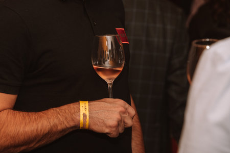Glass of rose wine held by a person at a premium wine tasting with friends and loved ones.
