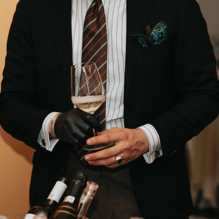 Glass of white wine held by a person at a premium wine tasting with friends and loved ones.の写真素材