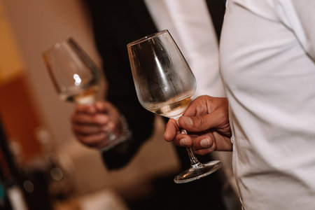 Glass of white wine held by a person at a premium wine tasting with friends and loved ones.