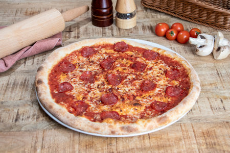 Pizza with salami and mushrooms on a rustic wooden tableの写真素材