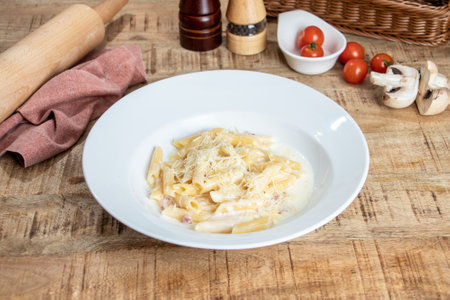 Penne pasta with ham and parmesan cheese on wooden backgroundの写真素材