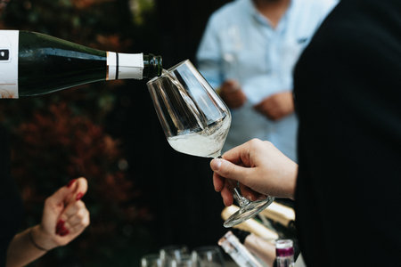 Close-up of two hands pouring champagne from bottle into glass.の写真素材