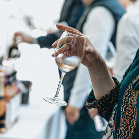 Closeup of female hand holding a glass of wine on a partyの写真素材