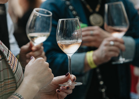 Close-up of female hands with glasses of white wine on partyの写真素材