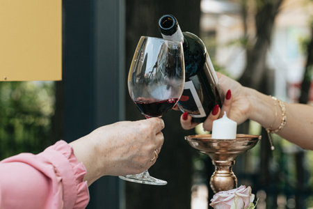 Female hands holding a glass of red wine and a bottle of wineの写真素材