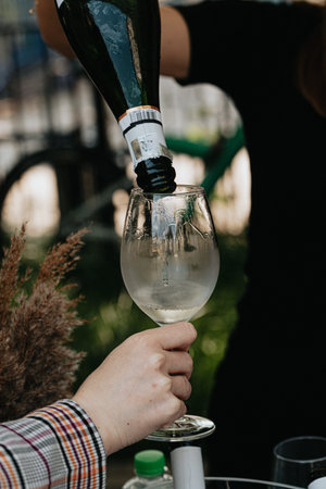 Close-up of a female hand pouring champagne from a bottle into a glass