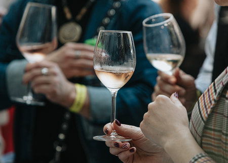 cropped shot of people clinking glasses with white wine during party