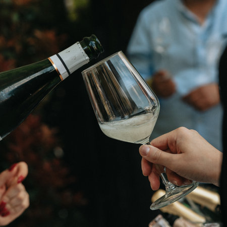 Close-up of two hands holding a glass of champagne and a bottle.の写真素材