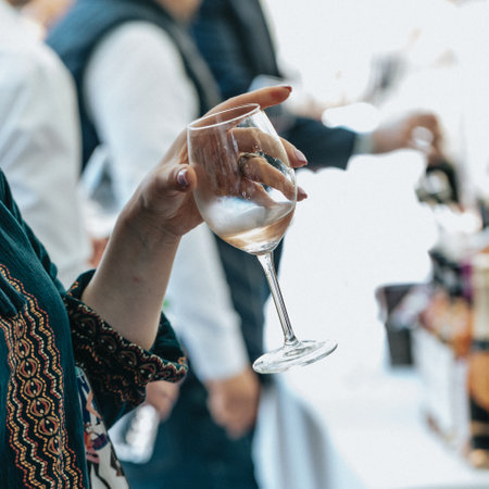 Close up of woman hands holding a glass of wine on the partyの写真素材