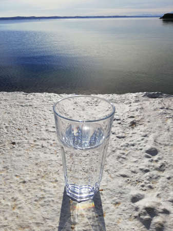 Glass of water on the beton with sea viewの写真素材