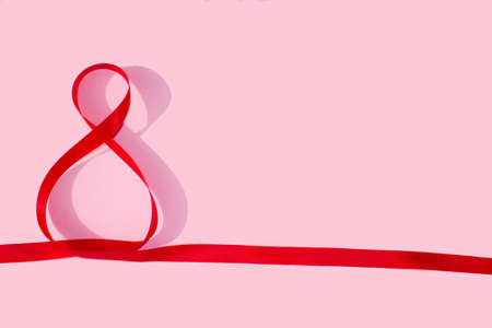Red silk ribbon shape of number eight on pink backgroundの写真素材