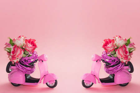 bouquet of roses in basket on backseat of cute pink scooter on pink background. Flower delivery.の写真素材