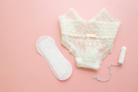 women intimate hygiene products - sanitary pads and tampon near womans panties on pink background.