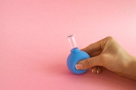 female hand with French manicure squeezes medical cosmetic jar for vacuum massage of body and face,...