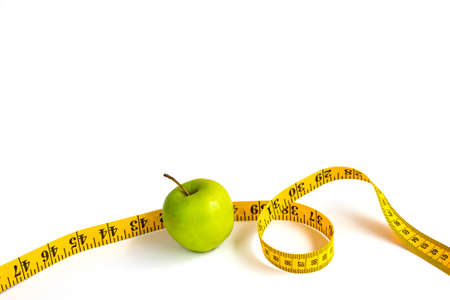 Green apple and measuring tape  with centimeters and inches isolated on white background.の写真素材