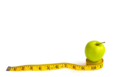 Green apple and measuring tape  with centimeters and inches isolated on white background.