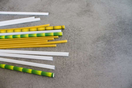 several replacements of plastic macaroni cocktail tubes, bioplastics and bamboo in the foreground blured tubes on a dark grey table. Environment. Saving nature. Bio matireal.の写真素材