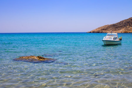 a small fishing boat drifting in the blue azure sea among the rocks and mountains