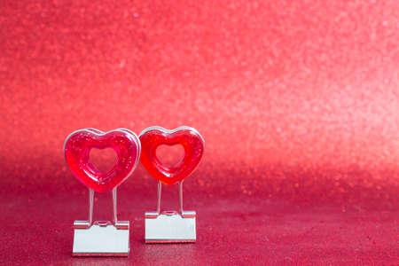 Two red hearts on a stand in the foreground on a red background with bokeh.の写真素材