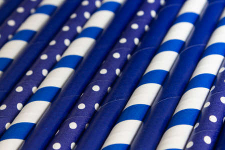 background of many blue paper tubes with white pea and cocktail strips lie diagonally across the screen in close upの写真素材