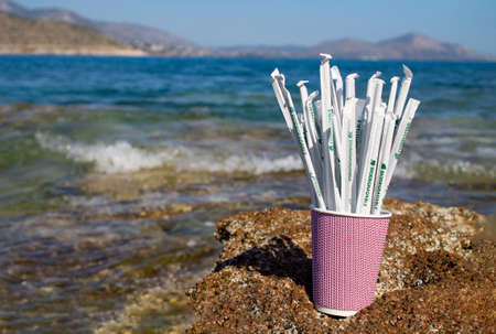 Greece. Athens. 13.05.2020. Paper drinking straws in paper cup outside on rocks next to seaの写真素材