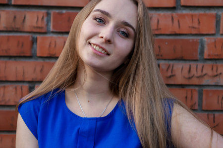 A cute girl in a blue blouse, with a chain around her neck, with long blond hair and blue eyes,...