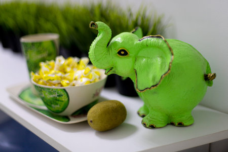 OMSK, RUSSIA, MAY 08, 2020: Green elephant figurine. It stands on a shelf next to a kiwi and a mug...