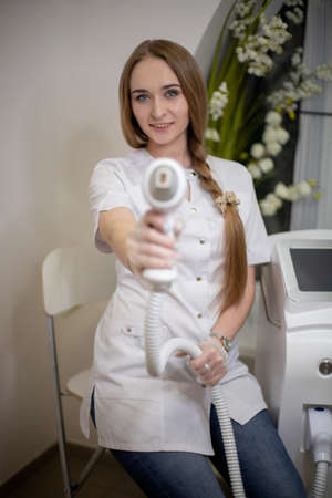 OMSK, RUSSIA, MAY 08, 2020: Manipula for laser hair removal close-up. The girl holds the handle of the epilation device with her hand.のeditorial素材