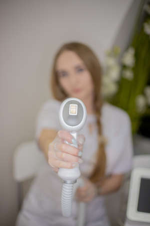OMSK, RUSSIA, MAY 08, 2020: Manipula for laser hair removal close-up. The girl holds the handle of the epilation device with her hand.のeditorial素材