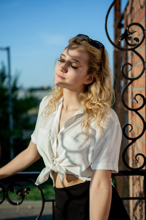 A young girl with sunglasses is shadowed by a patterned fence. A blonde in a white shirt.の写真素材