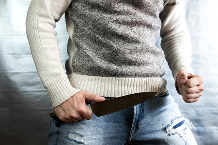 An evil man holds a shiny steel knife in his hand, a killer in action. A maniac is hunting a victim.