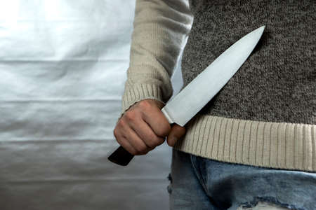 An evil man holds a shiny steel knife in his hand, a killer in action. A maniac is hunting a victim.の写真素材