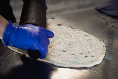 Process of making pizza in a pizzeria, hands in blue glovesの写真素材