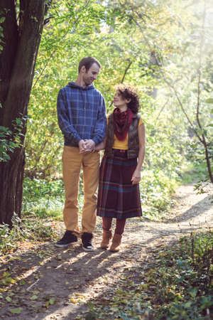 Loving couple in bright clothes walking together in the parkの写真素材