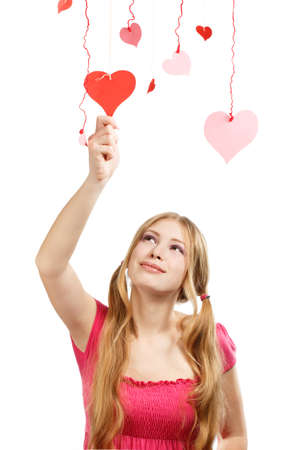 Beautiful young smiling woman touchs designer red and pink paper valentine hearts hanging on colored threads の写真素材