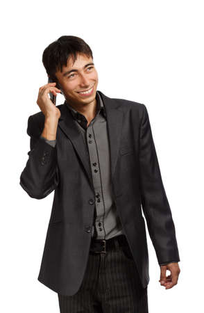 Young businessman in dark grey suit stands with mobile phone isolated on white backgroundの写真素材