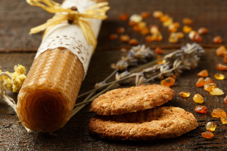 Still life with honey candle, oatmeal cookies, dried lavender and marine baltic amber on wooden table backgroundの写真素材